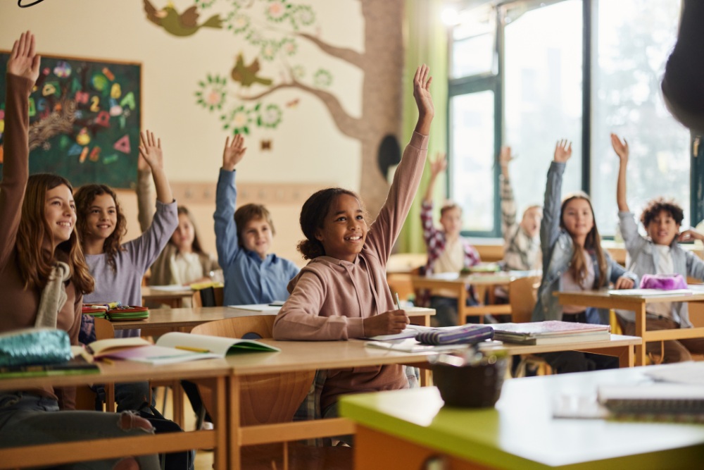 Happy elementary students raising their hands